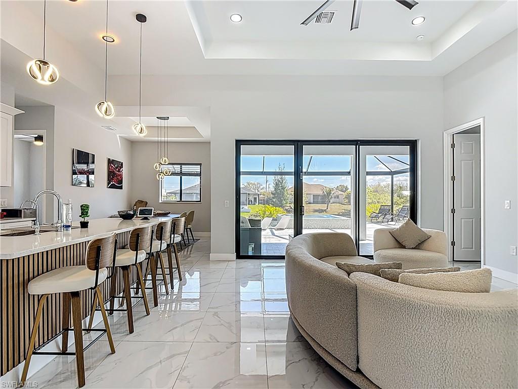Living room featuring light marble finish flooring, recessed lighting, and a raised ceiling