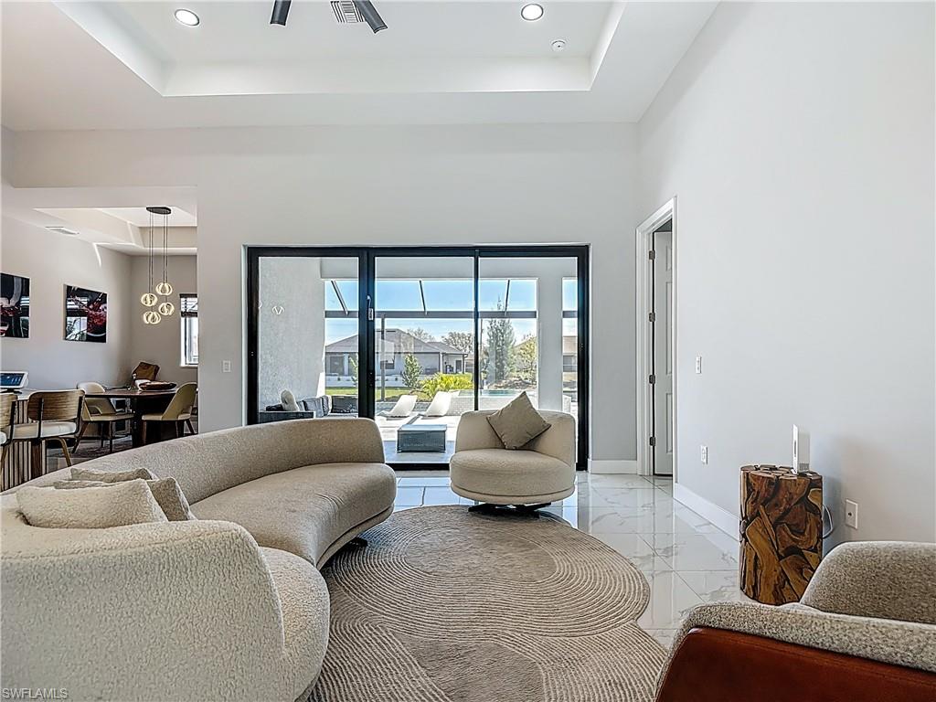 Living area with light marble finish floors, recessed lighting, and a raised ceiling