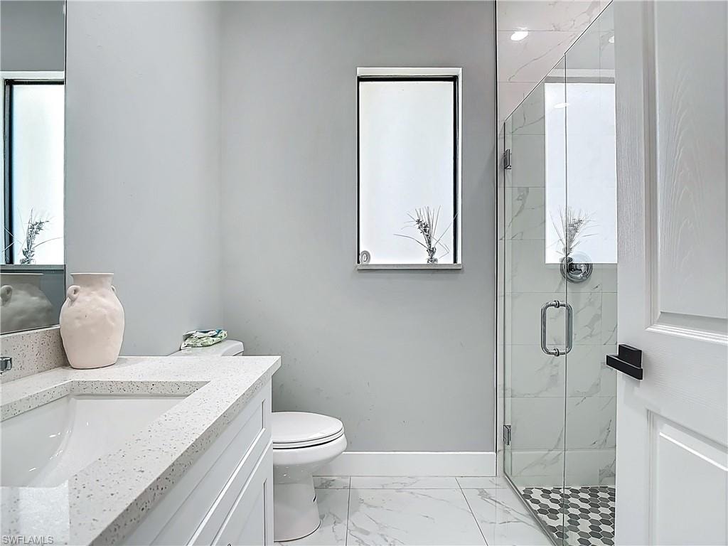 Full bathroom with vanity, a marble finish shower, and light marble finish floors