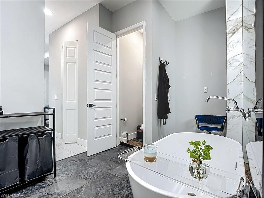 Full bathroom with stone tile flooring, a soaking tub, and vanity