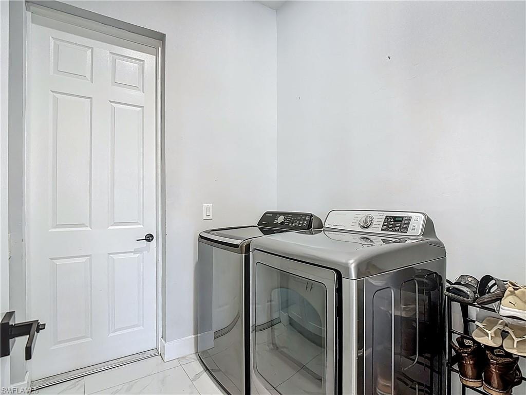 Laundry room featuring light marble finish floors and washing machine and dryer