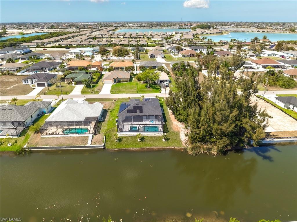 Aerial perspective of suburban area featuring a nearby body of water and a pool