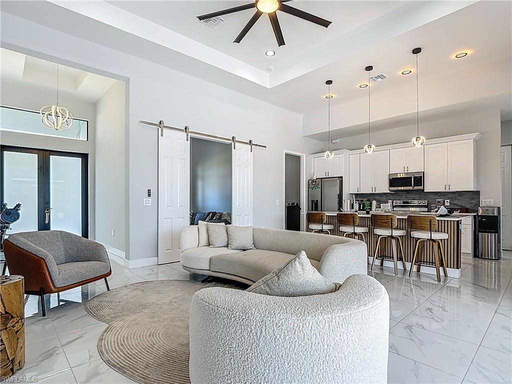 Living area featuring a barn door, ceiling fan, a high ceiling, recessed lighting, and french doors