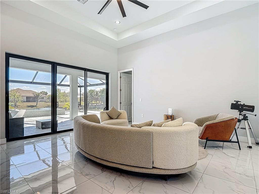 Living area featuring ceiling fan, a high ceiling, light marble finish flooring, and recessed lighting