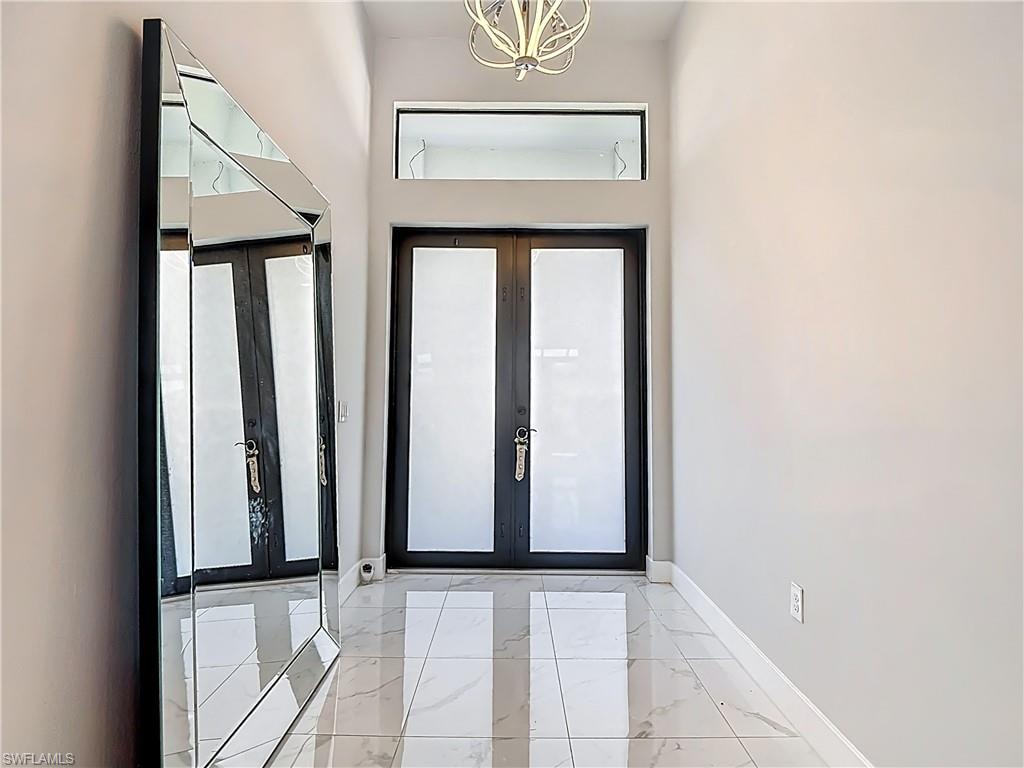 Foyer featuring french doors, hanging lights, and light marble finish floors