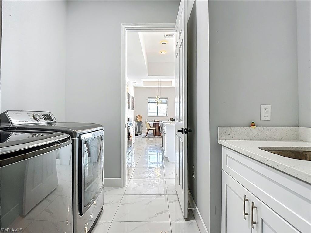 Laundry area with washing machine and clothes dryer and light marble finish flooring