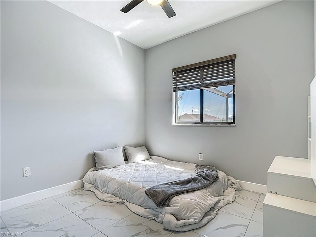 Bedroom with light marble finish floors and a ceiling fan