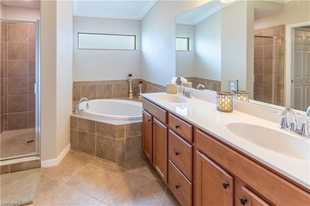 Bathroom with vanity, crown molding, shower with separate bathtub, and tile patterned flooring