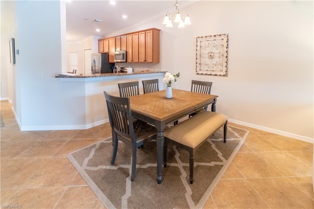 Tiled dining room featuring crown molding, a notable chandelier, and lofted ceiling