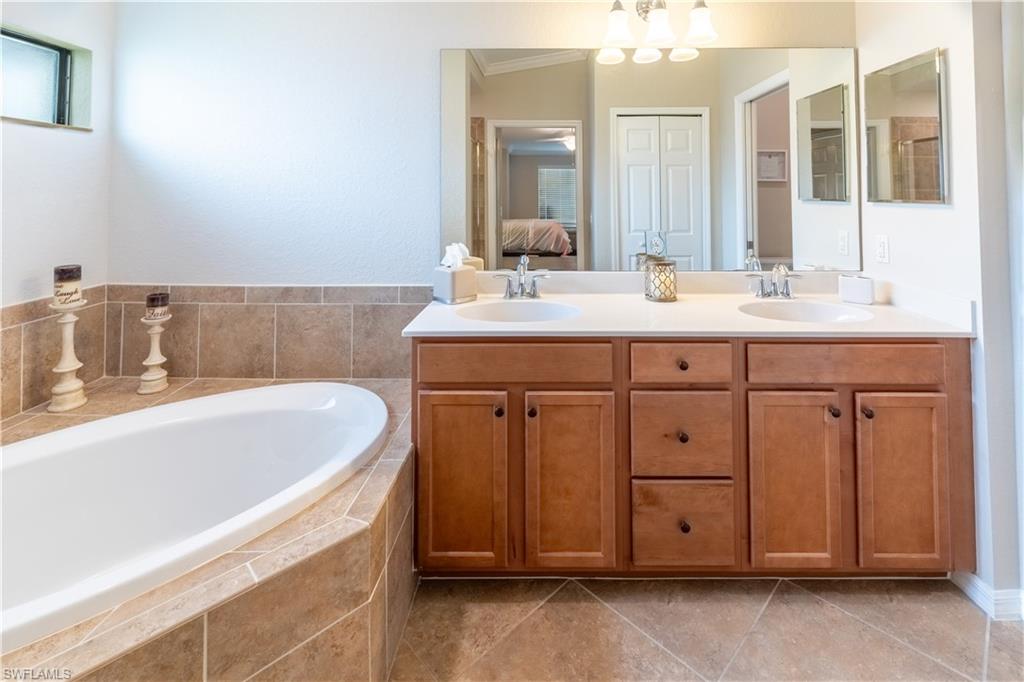 Bathroom with vanity, tiled bath, and tile patterned flooring