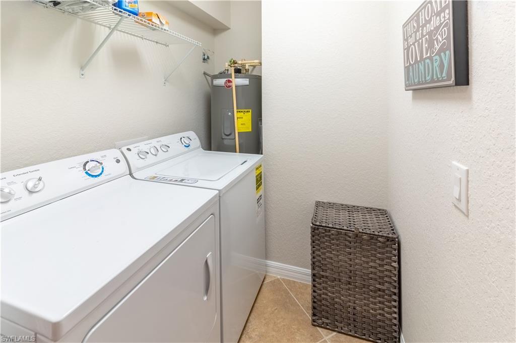 Washroom with electric water heater, washing machine and clothes dryer, and light tile patterned floors
