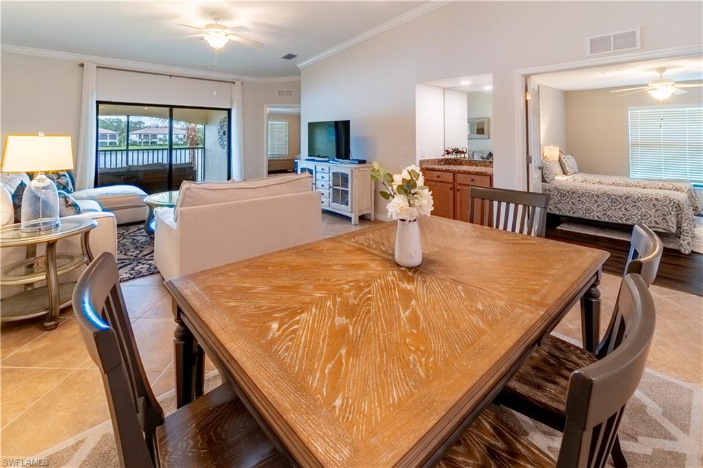 Tiled dining space with ornamental molding, vaulted ceiling, and ceiling fan