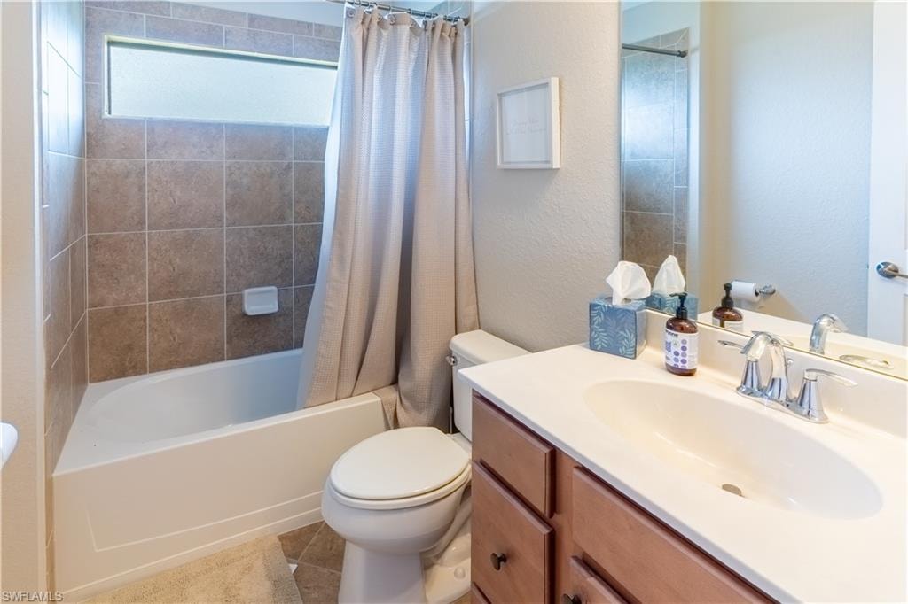 Full bathroom with vanity, toilet, shower / bathtub combination with curtain, and tile patterned flooring