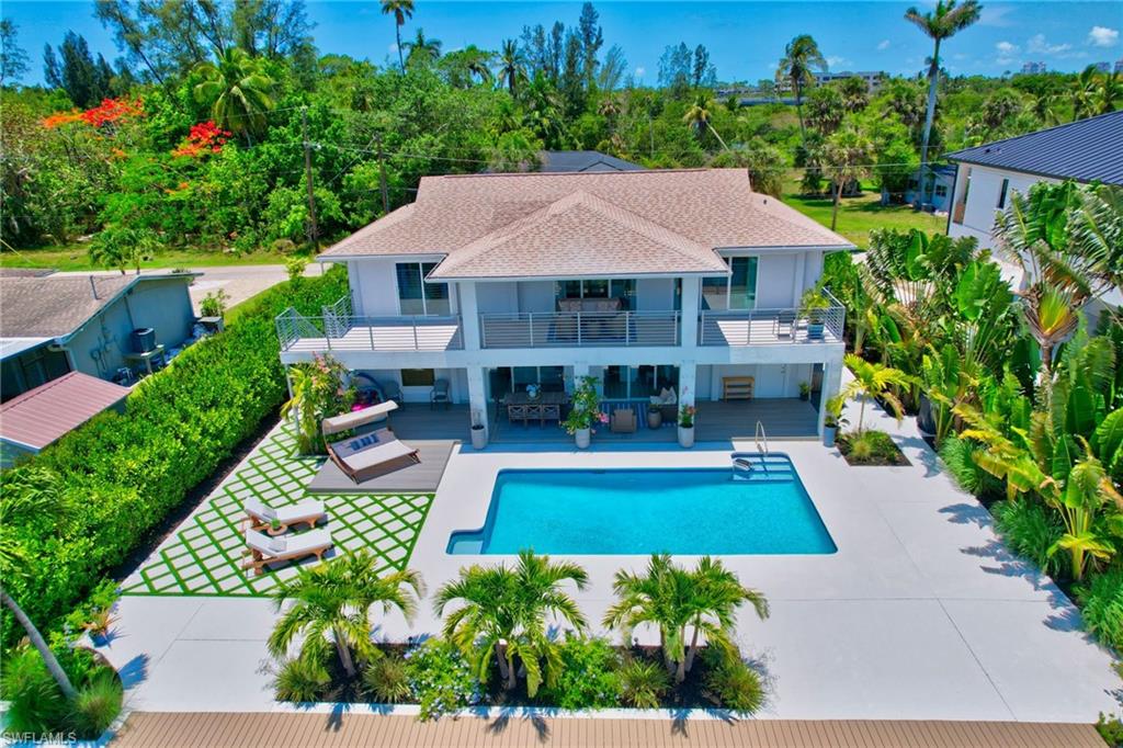 Rear view of property with a patio area, an outdoor pool, a shingled roof, and a balcony