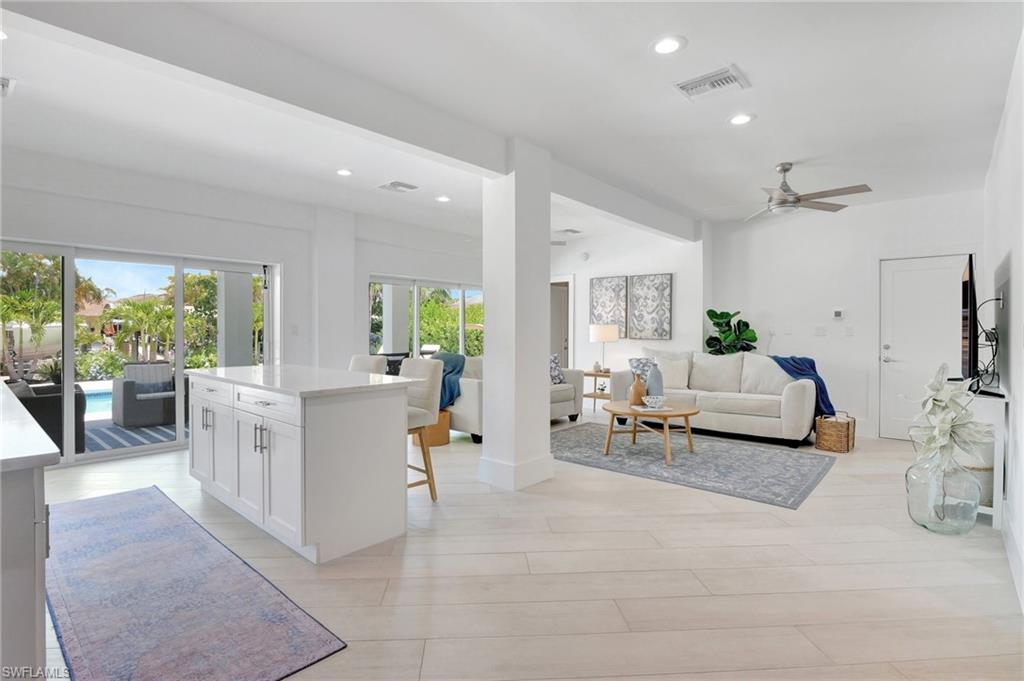 Kitchen with open floor plan, a center island, white cabinets, recessed lighting, and ceiling fan