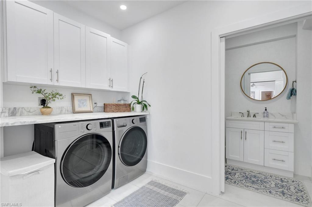 Laundry room featuring cabinet space, washer and clothes dryer, light tile patterned flooring, and recessed lighting