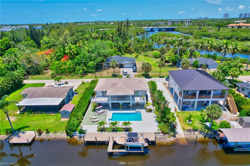 Aerial view of property and surrounding area featuring a nearby body of water and a pool