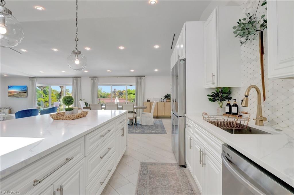 Kitchen featuring white cabinetry, light stone counters, and stainless steel appliances