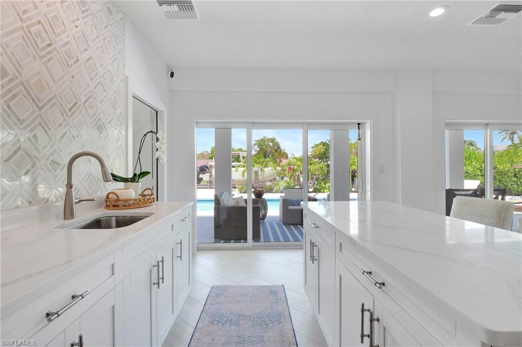Kitchen featuring light stone countertops, white cabinetry, a center island, and recessed lighting