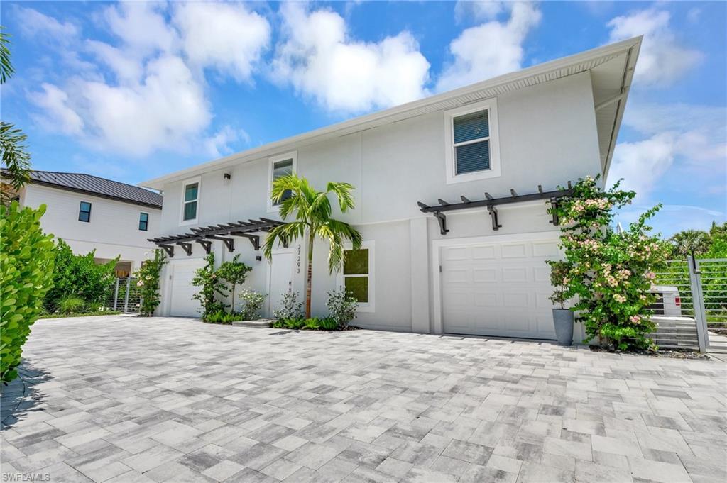 View of front of property with an attached garage, stucco siding, driveway, and a pergola
