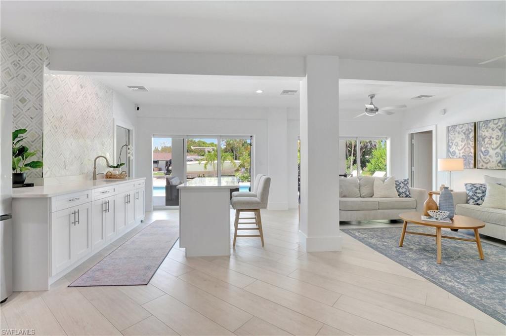 Kitchen featuring a breakfast bar area, white cabinetry, healthy amount of natural light, open floor plan, and recessed lighting