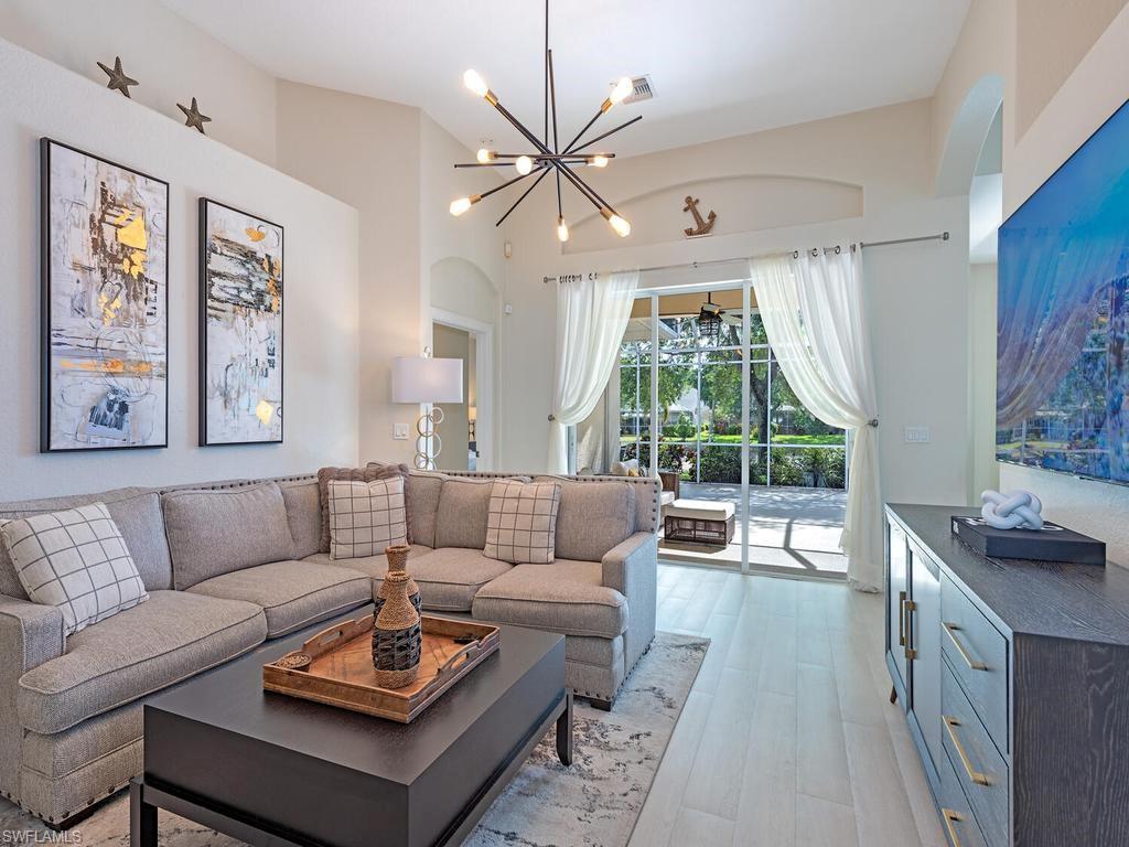 Spacious living area featuring high vaulted ceilings, light wood-finish flooring, and a contemporary sputnik chandelier
