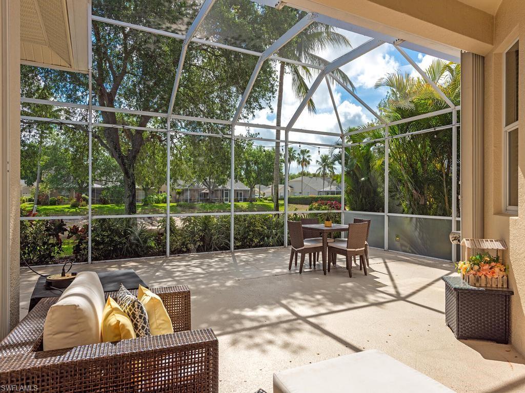 Spacious screened lanai featuring a concrete patio, vaulted screen enclosure, and lush perimeter landscaping