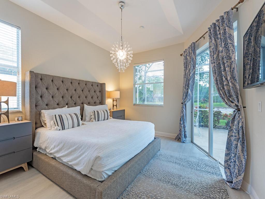 Bedroom featuring a tufted upholstered headboard, a tray ceiling, and a contemporary chandelier