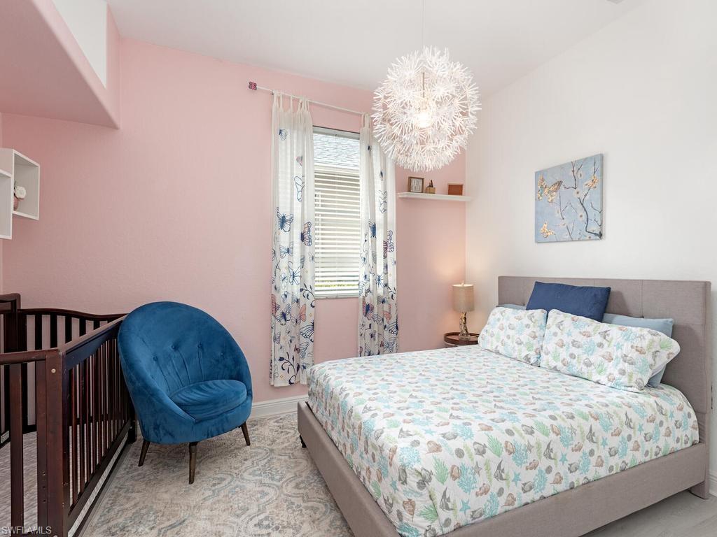 Bedroom featuring a light gray upholstered bed frame, a prominent window with blinds, and decorative curtain rods