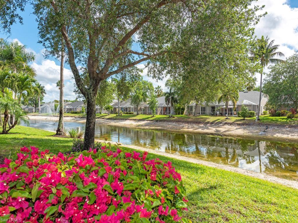 Lakeside setting with a central fountain, mature trees, vibrant bougainvillea, and lush green landscaping surrounding the tranquil water feature