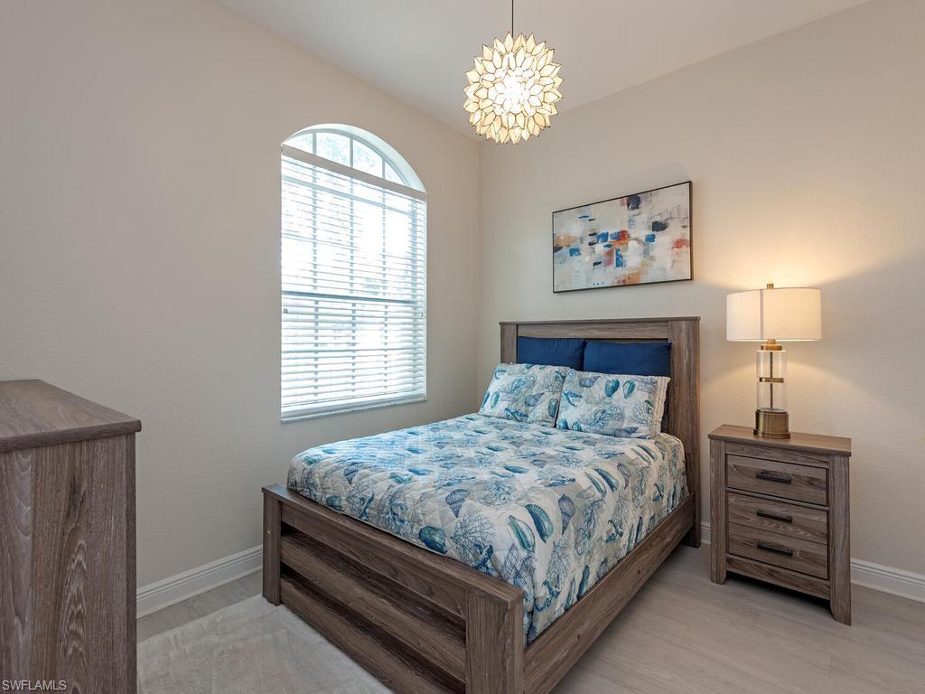 Arched window with blinds, light wood-finish flooring, and a contemporary ceiling fixture