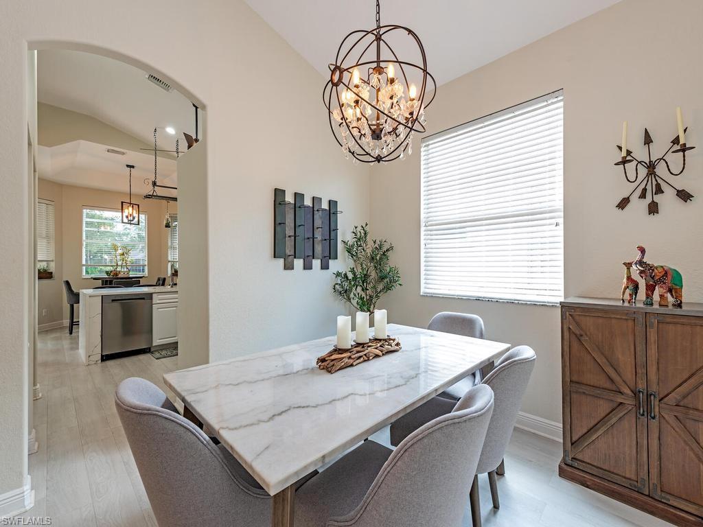Dining area featuring a crystal-adorned spherical chandelier, a large window with blinds, and light-toned wood-finish flooring