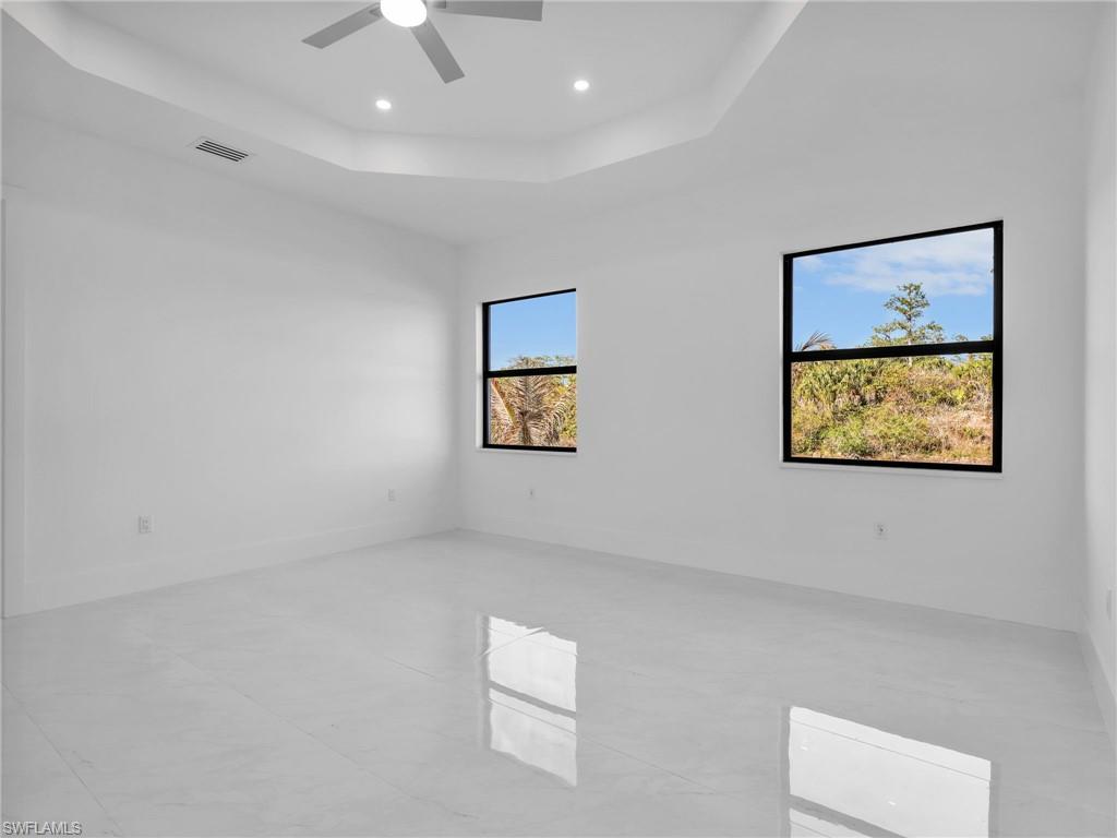 Unfurnished room with a raised ceiling, ceiling fan, and recessed lighting