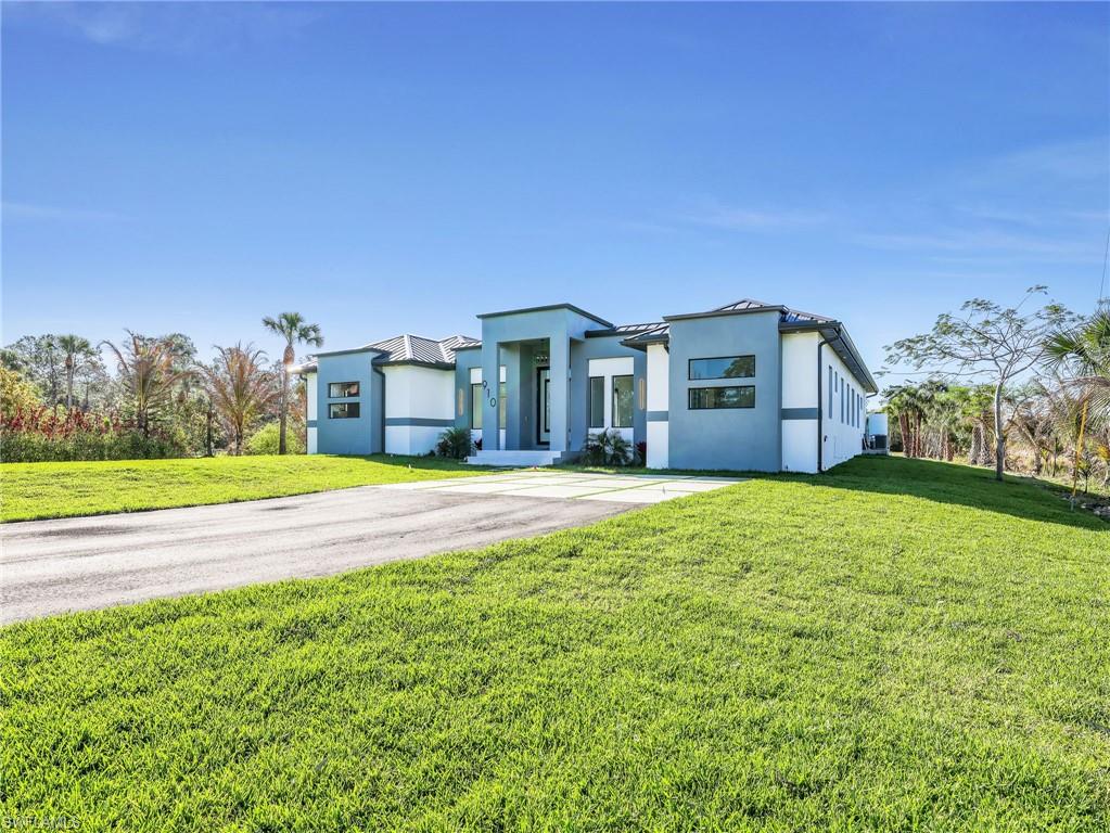 Modern home featuring stucco siding, a front lawn, a standing seam roof, and driveway