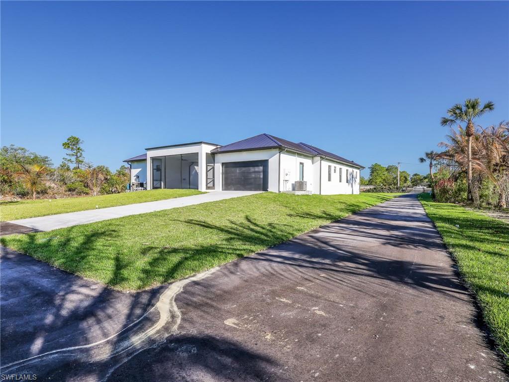 View of front of home featuring a front yard, driveway, stucco siding, and a garage