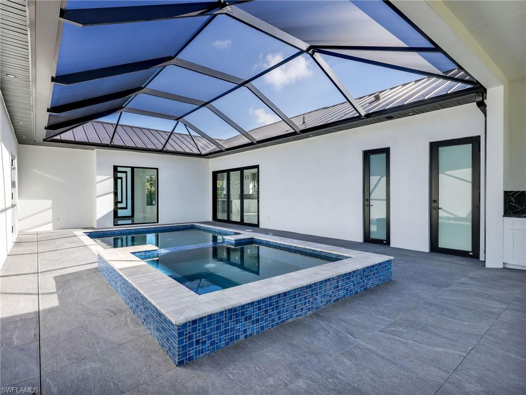 Integrated pool / spa featuring a sunroom, a patio, and glass enclosure