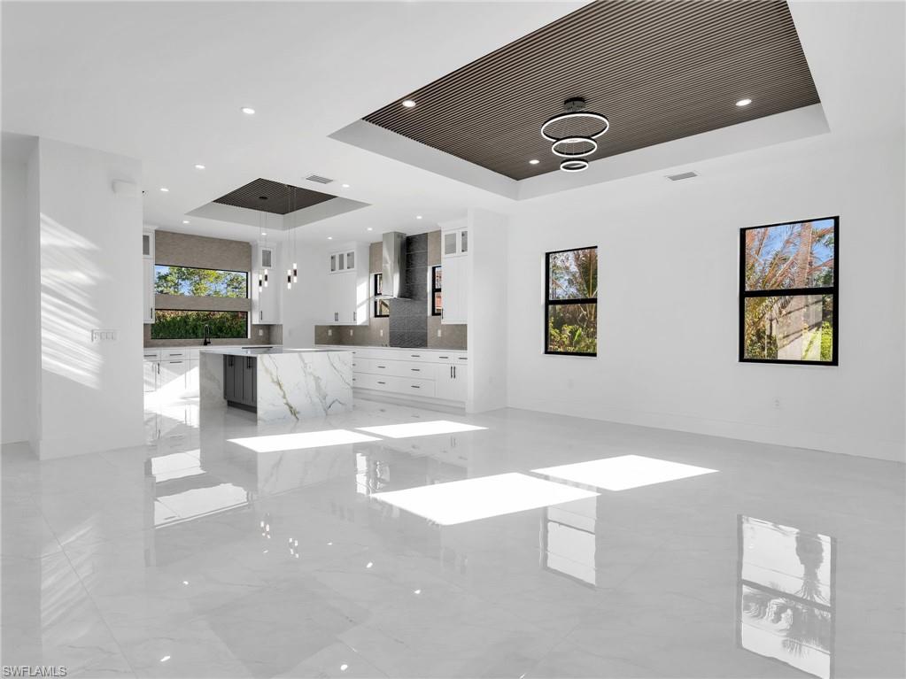 Unfurnished living room with a tray ceiling and baseboards