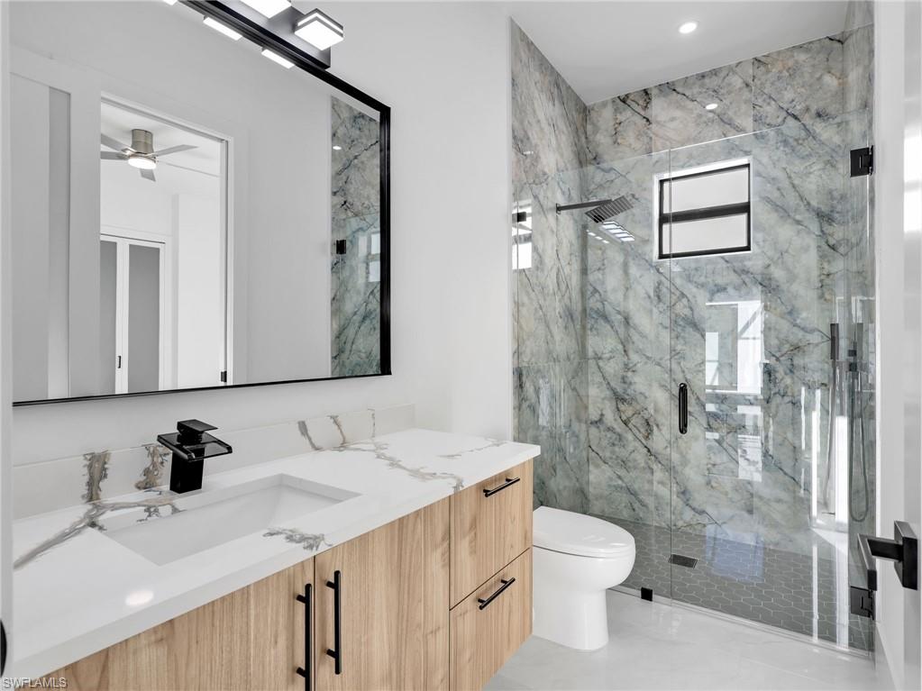 Bathroom with vanity and a marble finish shower
