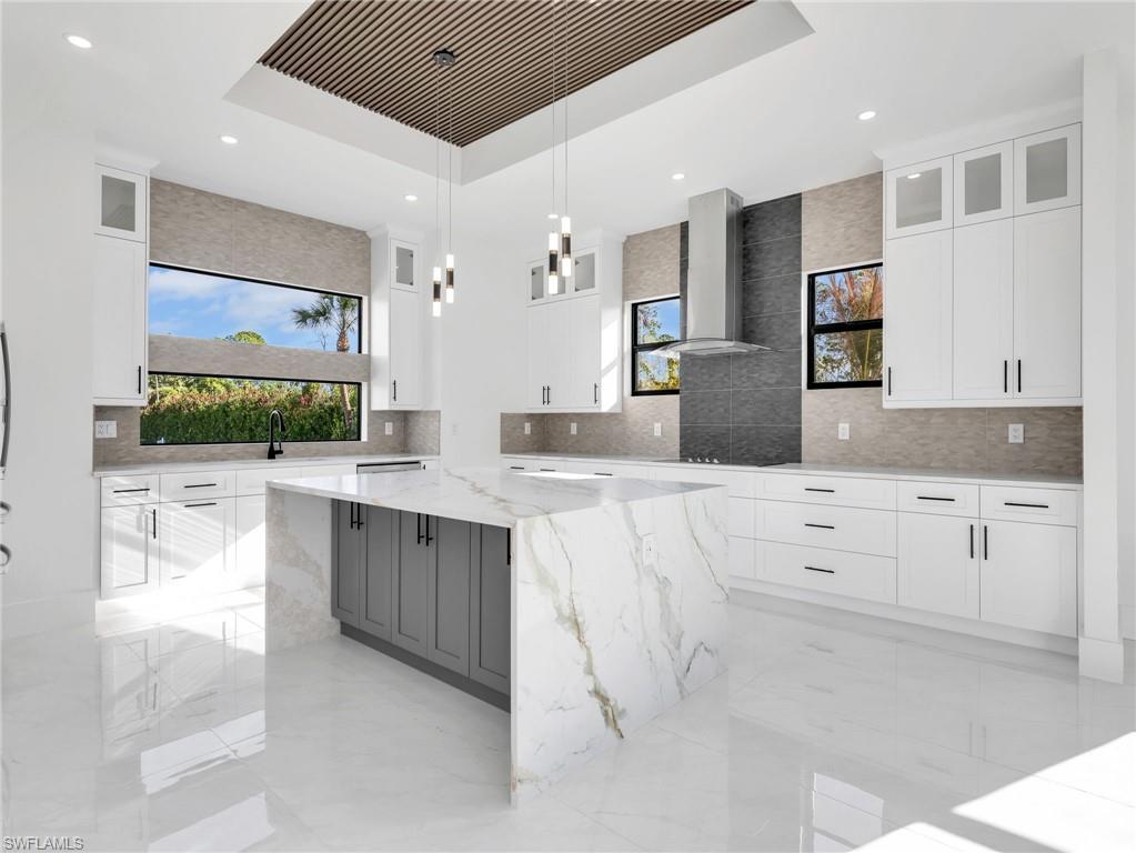 Kitchen with plenty of natural light, light stone countertops, and glass fronted cabinets