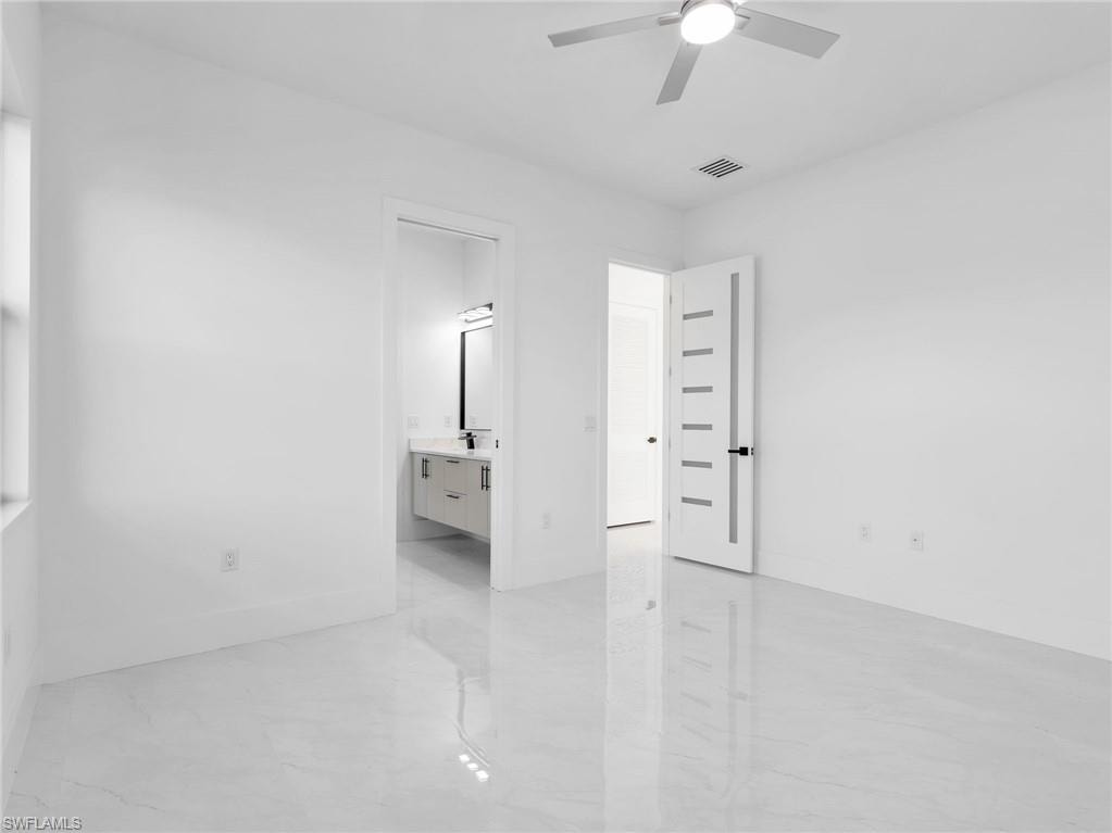Unfurnished bedroom featuring ensuite bath, a ceiling fan, and light marble finish flooring