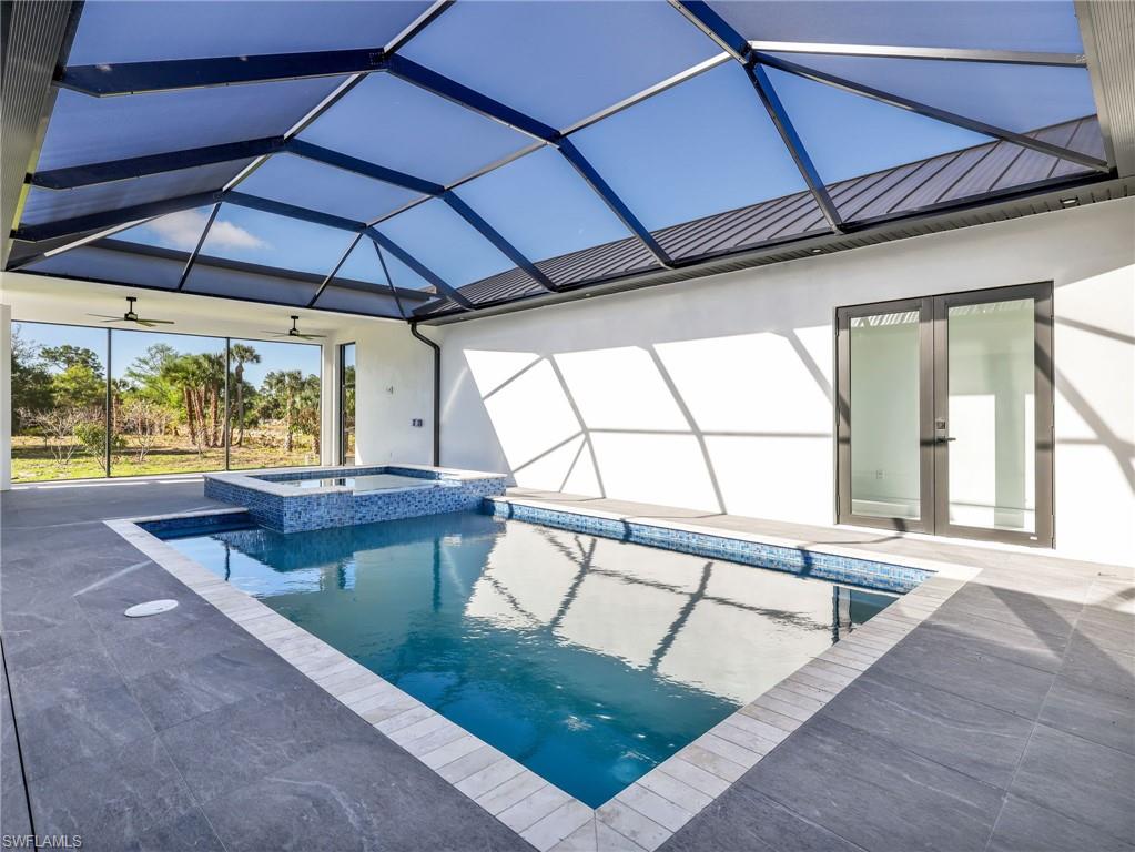 Combined pool / hot tub with a sunroom, french doors, glass enclosure, and a patio area