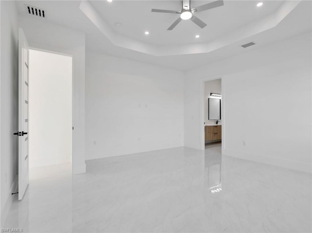 Empty room with ceiling fan, a raised ceiling, and recessed lighting