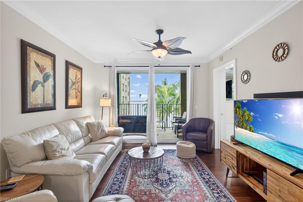 Living area with ornamental molding, ceiling fan, and dark wood-style flooring