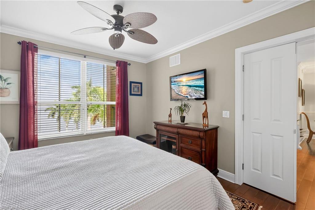 Bedroom with crown molding, dark wood finished floors, and a ceiling fan