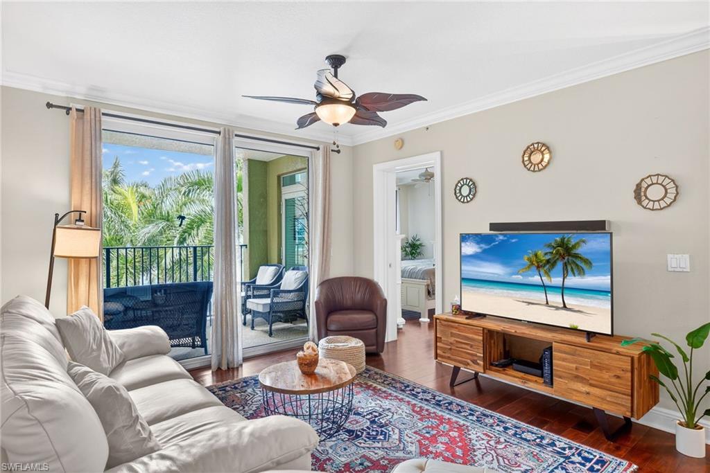 Living area featuring crown molding, dark wood-type flooring, and a ceiling fan