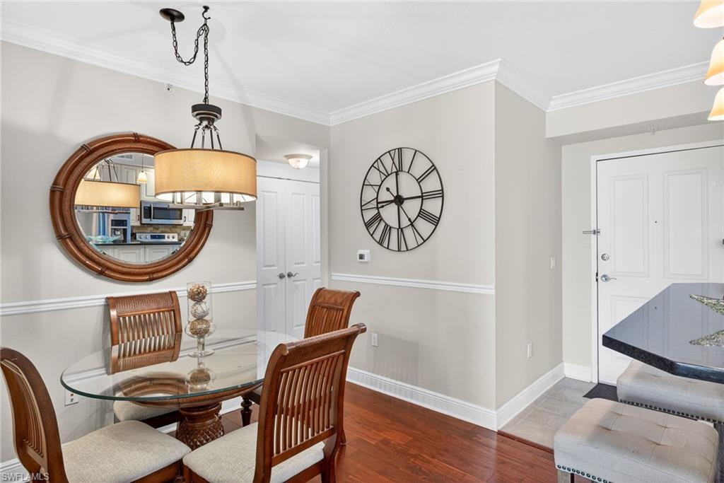 Dining area with ornamental molding and dark wood-type flooring