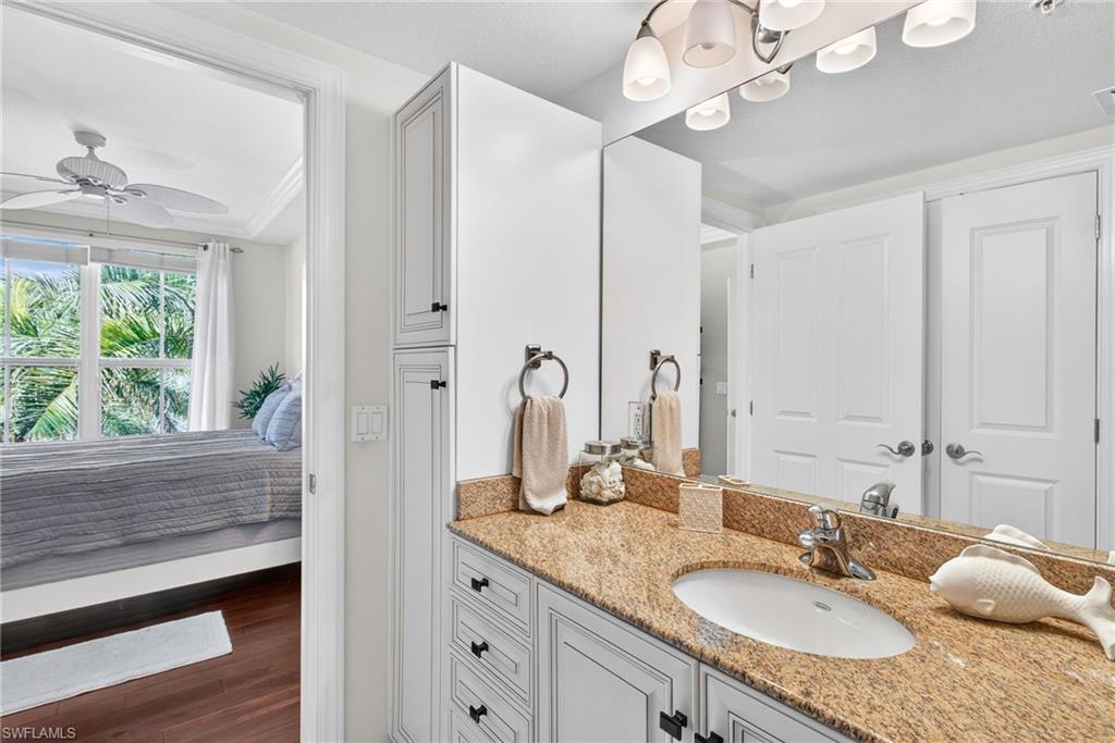 Bathroom featuring ensuite bath, vanity, dark wood-type flooring, and a ceiling fan