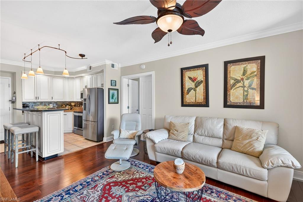 Living area with crown molding, light wood-style floors, and a ceiling fan