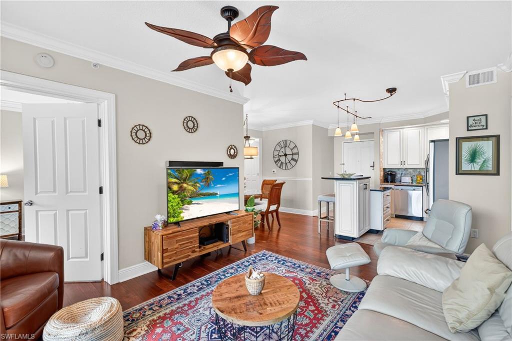 Living room featuring crown molding, dark wood-type flooring, and ceiling fan