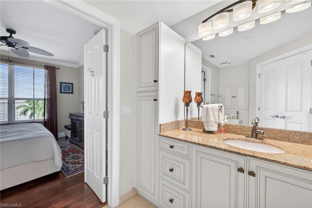 Ensuite bathroom featuring vanity, ceiling fan, and light wood-style flooring